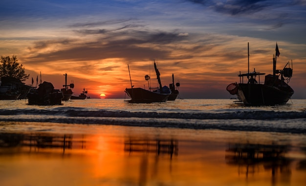 Silhouette Fischerboote im Meer mit warmer, schwacher Beleuchtung des Sonnenuntergangs und dunklem Schatten.