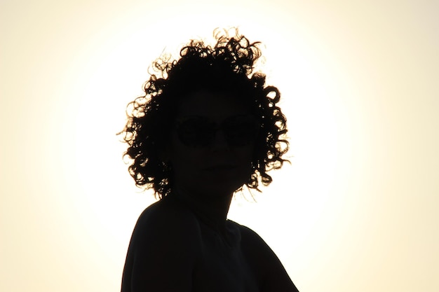 Silhouette Frau mit lockigem Haar gegen den Himmel bei Sonnenuntergang