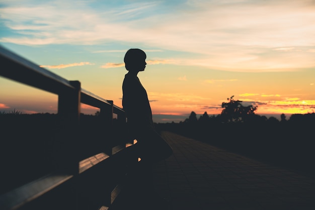 Silhouette Frau mit Traurigkeit bei Sonnenuntergang allein.