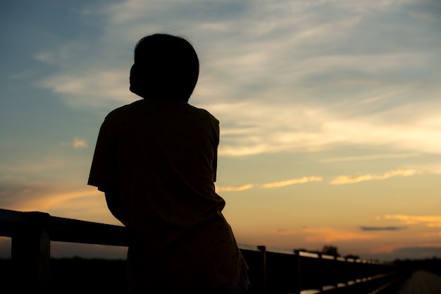 Silhouette Frau mit Traurigkeit bei Sonnenuntergang allein.