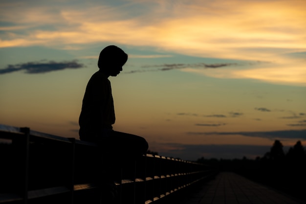 Silhouette Frau mit Traurigkeit bei Sonnenuntergang allein.