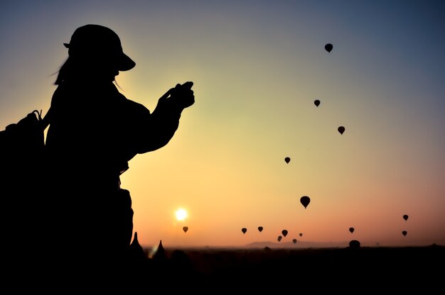 Silhouette frau reisende nehmen foto ansicht sonnenaufgang mit vielen heißluftballons über bagan in myanmar.