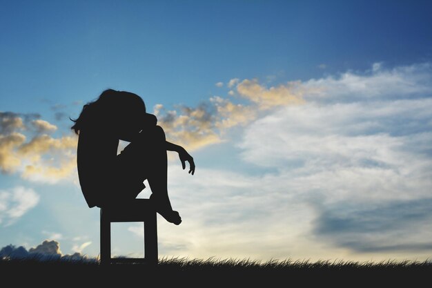 Foto silhouette frau sitzt auf einem stuhl gegen den himmel bei sonnenuntergang