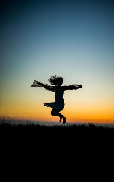 Silhouette Frau springt auf dem Feld gegen den Himmel bei Sonnenuntergang