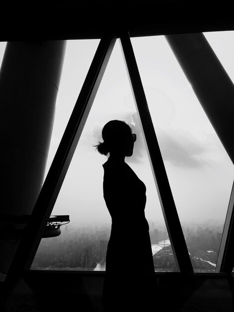 Foto silhouette frau steht am fenster gegen den himmel