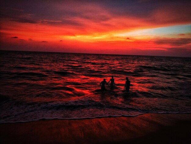 Foto silhouette freunde genießen im meer gegen den himmel bei sonnenuntergang