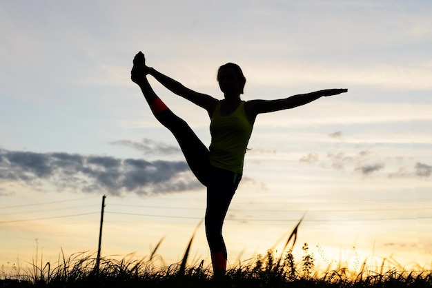 Silhouette junge frau, die yoga im hinterhof praktiziert