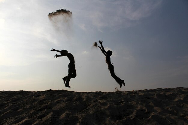 Foto silhouette-jungen springen bei sonnenuntergang am strand gegen den himmel