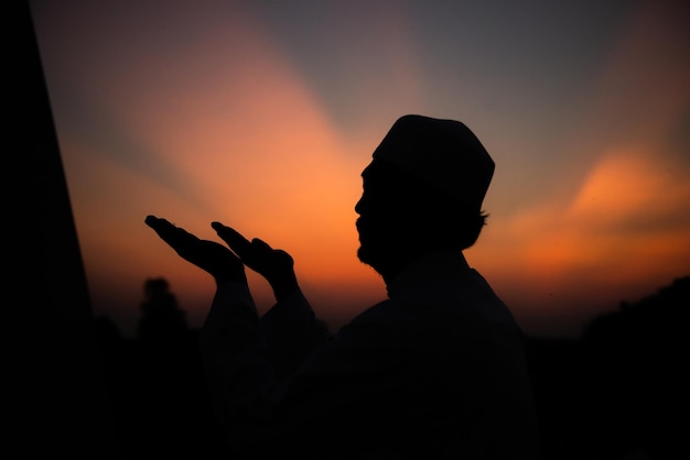 Silhouette Junger asiatischer muslimischer Mann, der auf dem Konzept des SunsetRamadan-Festivals betet