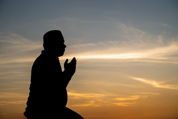 Silhouette Junger asiatischer muslimischer Mann, der auf dem Konzept des SunsetRamadan-Festivals betet