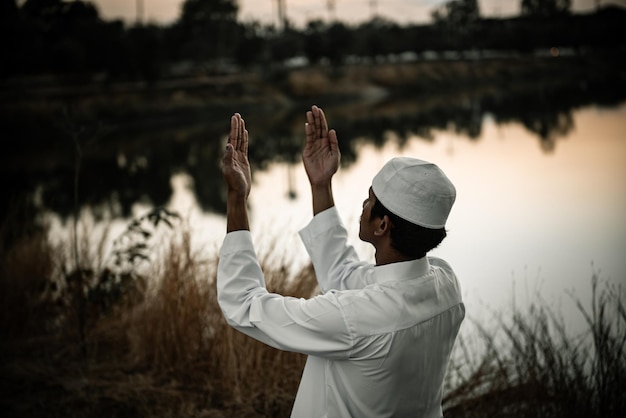 Silhouette Junger asiatischer muslimischer Mann, der auf dem Konzept des SunsetRamadan-Festivals betet