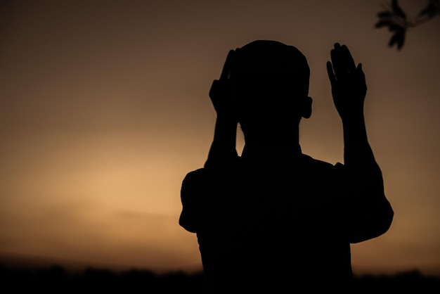 Silhouette Junger asiatischer muslimischer Mann, der auf dem Konzept des SunsetRamadan-Festivals betet