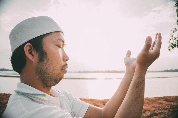 Silhouette Junger asiatischer muslimischer Mann, der auf dem Konzept des SunsetRamadan-Festivals betet