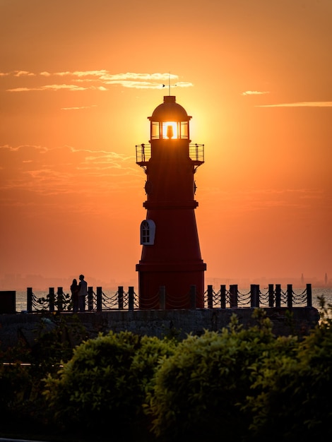 Foto silhouette leuchtturm am meer gegen orangefarbenen himmel