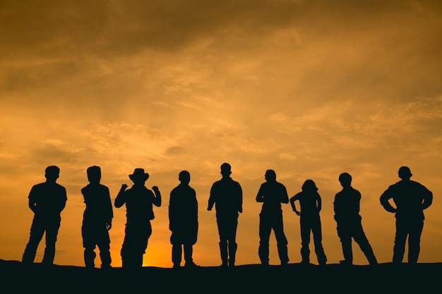 Foto silhouette-leute-team steht und schaut in der dämmerung nach vorne auf den hügel.