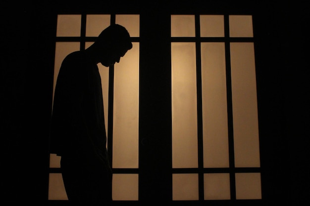 Silhouette Mann, der zu Hause am Fenster steht