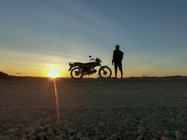 Silhouette Mann mit Motorrad bei Sonnenuntergang