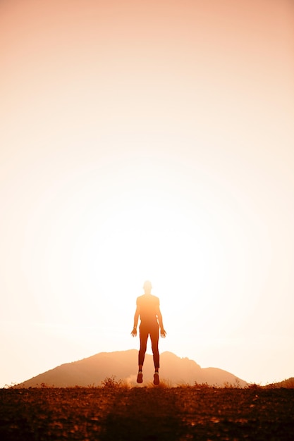 Silhouette Mann springt auf dem Feld gegen klaren Himmel bei Sonnenuntergang