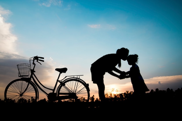 Silhouette Mutter Kuss Tochter mit Fahrrad