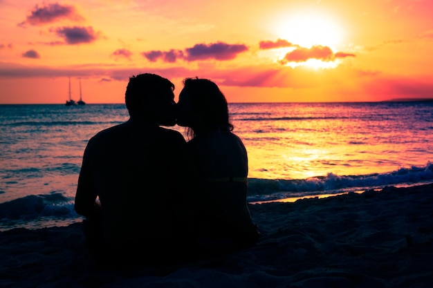 Silhouette-Paar küsst sich beim Sonnenuntergang am Strand gegen den Himmel
