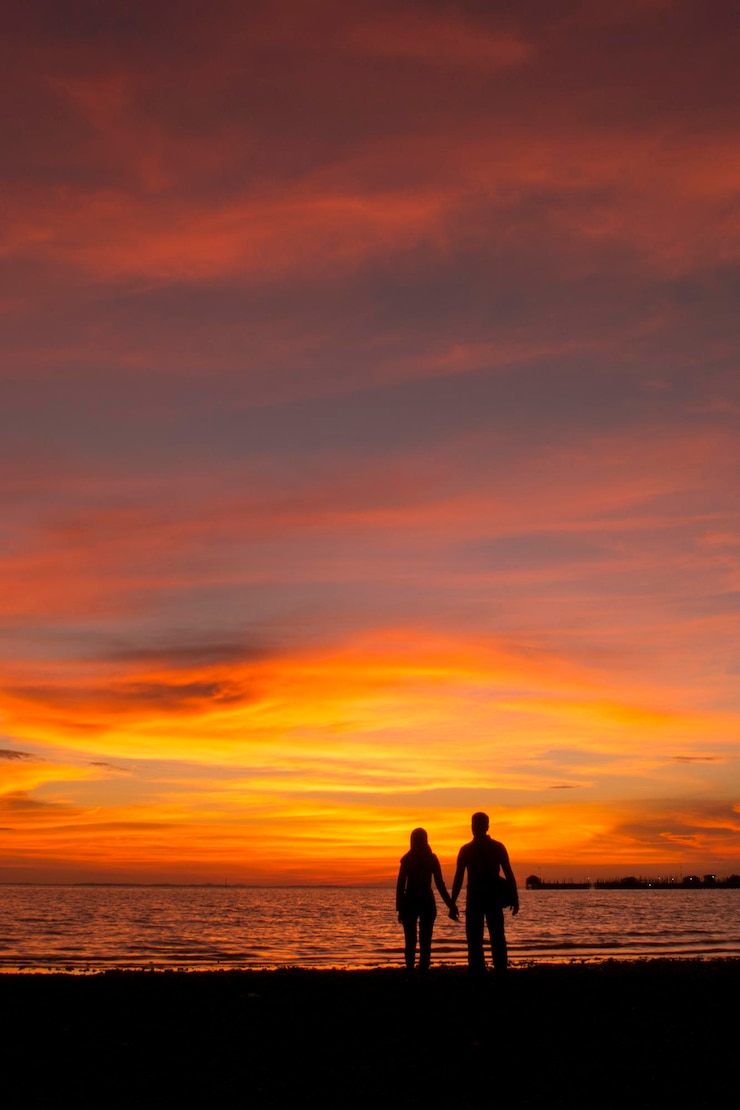 Foto silhouette-paar steht am strand gegen den himmel während des sonnenuntergangs