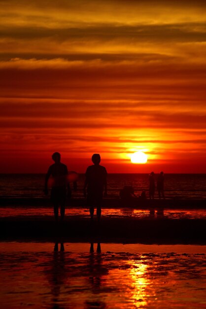 Foto silhouette-paar steht beim sonnenuntergang am strand gegen den himmel