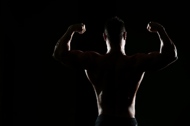 Silhouette Portrait eines jungen körperlich fitten Mannes, der seinen gut trainierten Körper zeigt muskulöser athletischer Bodybuilder Fitness Model posiert nach Übungen