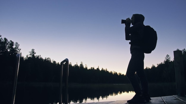 Silhouette Reisenden fotografieren malerische Aussicht im Wald Fluss Holzsteg Eine Frau schießen schöne dunkle Magie Nacht-Look Mädchen nehmen Foto vor der Kamera