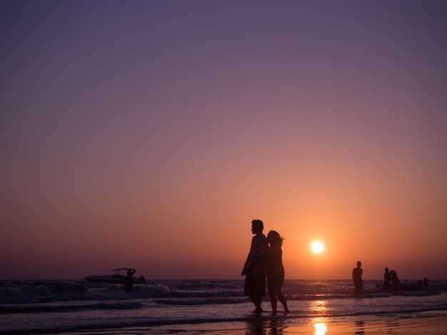 Silhouette Schatten eines Paares in Liebe zu Fuß am Strand mit Sonnenuntergang. Konzept des Urlaubsstrandes