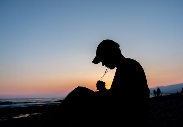 Silhouette Teen in Frieden am Strand sitzen