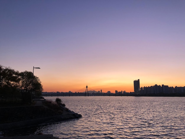 Silhouette von Gebäuden am Meer gegen den Himmel bei Sonnenuntergang