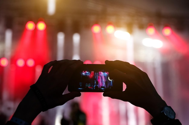 Silhouette von Händen mit einem Smartphone bei einem großen Musikfestival