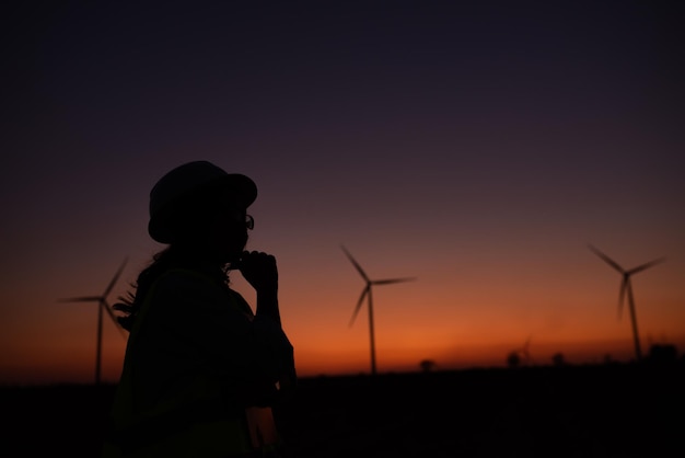 Silhouette von Ingenieurinnen, die arbeiten und den Bericht in der Windturbinenfarm Power Generator Station auf MountainThailand-Leuten halten