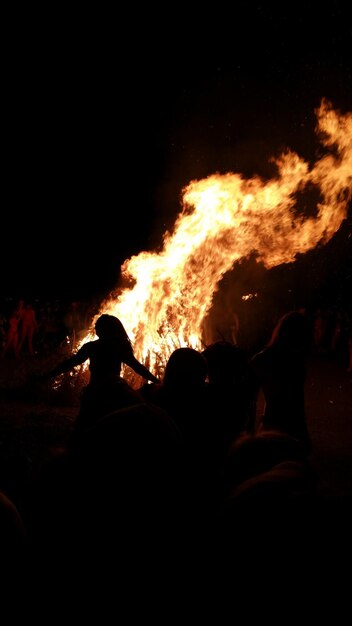 Silhouette von Menschen am Lagerfeuer in der Nacht