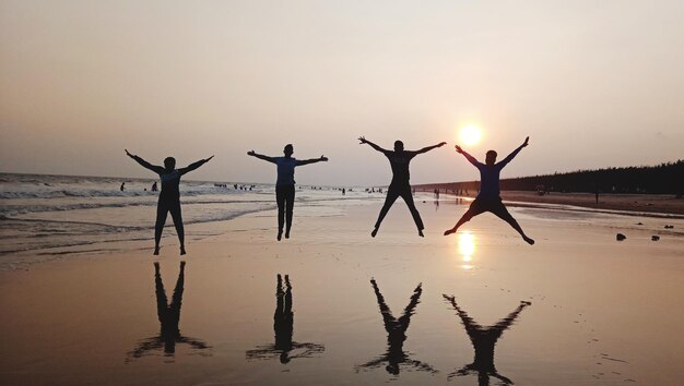 Foto silhouette von menschen am strand gegen den himmel beim sonnenuntergang