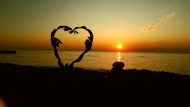 Silhouette von Menschen am Strand gegen den Himmel beim Sonnenuntergang