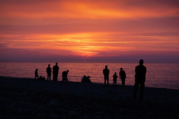 Foto silhouette von menschen an einem strand, die den sonnenuntergang genießen