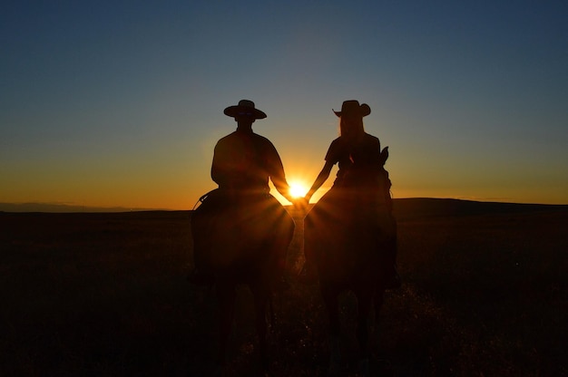 Foto silhouette von menschen, die bei sonnenuntergang reiten