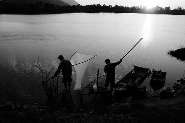 Foto silhouette von menschen, die im see angeln