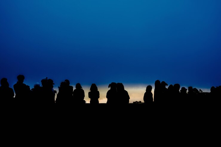 Foto silhouette von menschen, die nachts gegen den klaren blauen himmel stehen