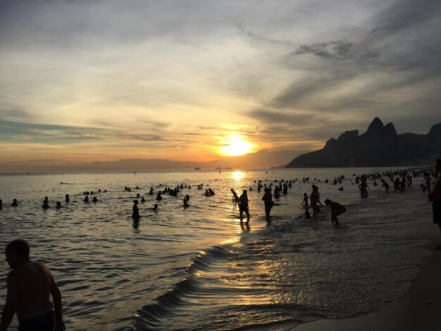 Foto silhouette von menschen, die sich beim sonnenuntergang im meer erfreuen