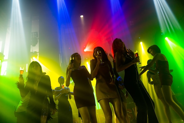 Foto silhouette von menschen tanzen im disco-nachtclub zu musik von dj auf der bühne