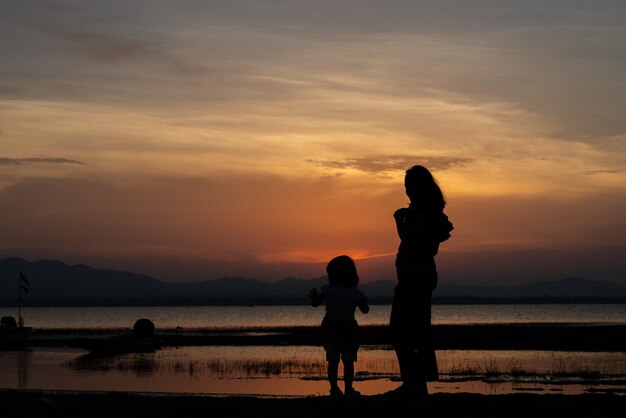 Silhouette von Mutter und Tochter bei SonnenuntergangThailänderGlückliches FamilienkonzeptMuttertagskonzept