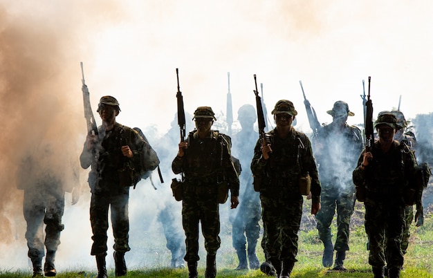 Silhouette von nicht erkannten Soldaten mit Gewehr gehen durch Rauch