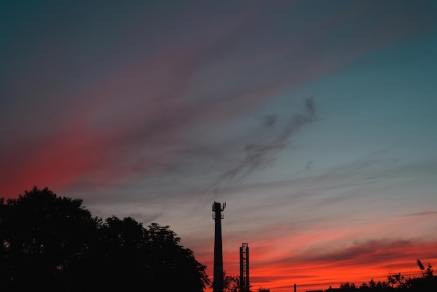 Silhouette von Rohren der chemischen Industriefabrik vor dem Hintergrund der dramatischen Landschaft des roten Sonnenunterganghimmels im Freien Kopierraum