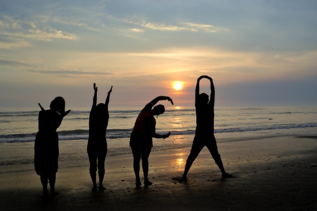 Silhouette von vier Leuten, die bei Sonnenuntergang an der Küste spielen Goldene Stunde