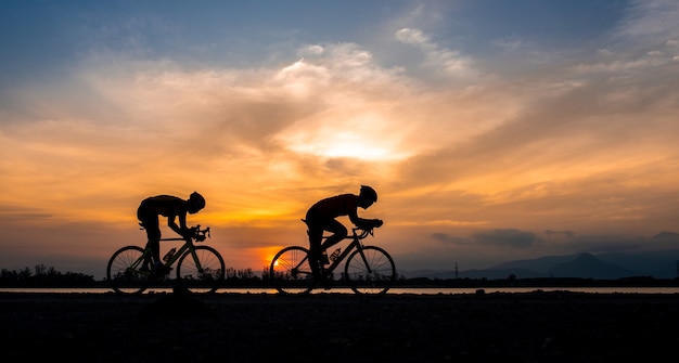 Foto silhouette zwei rennradradfahrermann, der am morgen radelt.