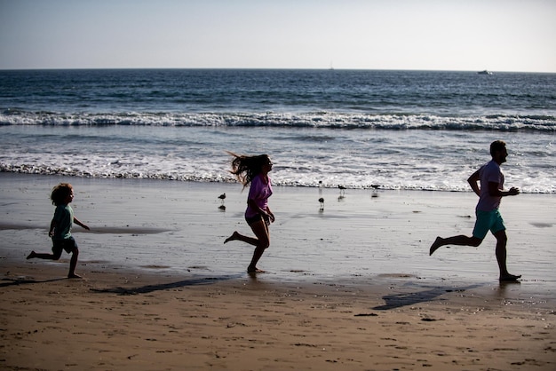 Silhouetten von Familien, die bei Sonnenaufgang am Meeresstrand joggen Outdoor-Training Silhouetten von Läufern spor