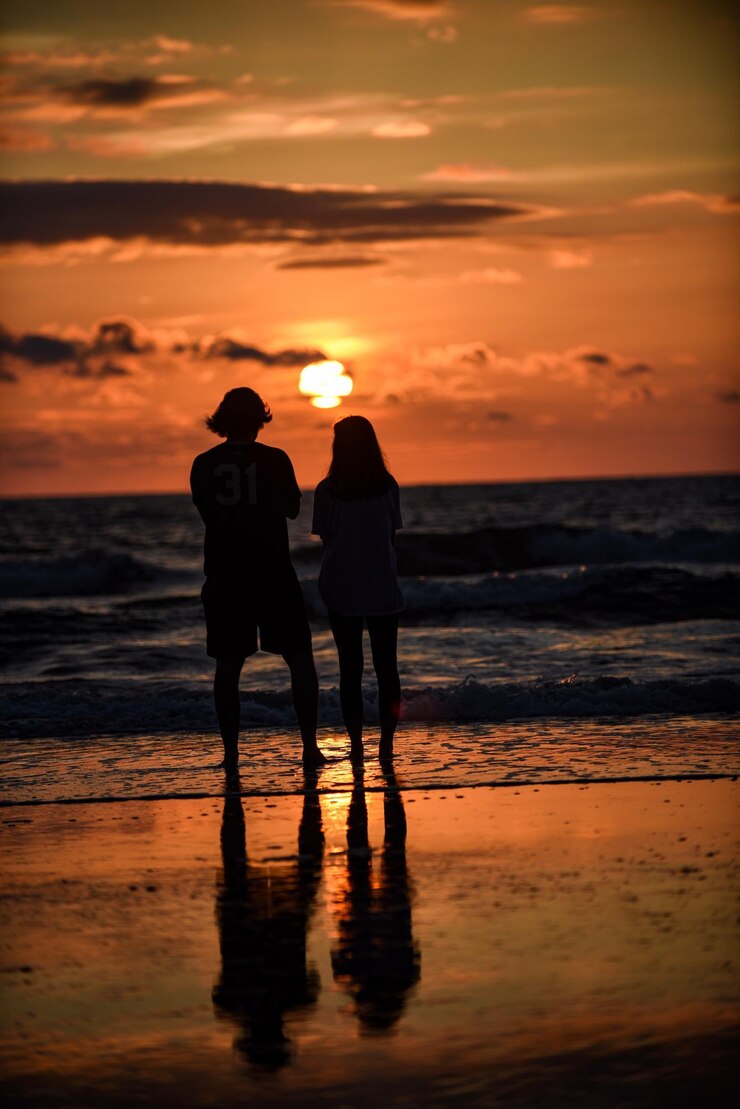 Foto silhouetten von freunden, die bei sonnenuntergang vor dem meer stehen