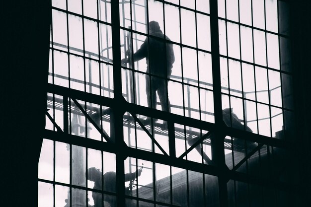 Foto silhouetten von männern, die über glasfenstern arbeiten